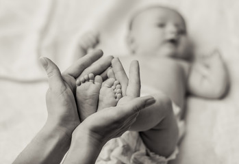 Mother holding tiny foot of newborn baby