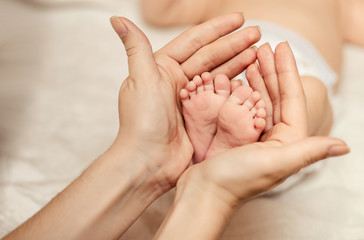 Obraz na płótnie Canvas Mother holding tiny foot of newborn baby