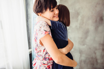 Fototapeta premium The mother embracing her daughter in the room