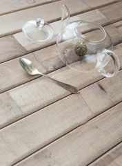 top view closeup of a glass tea pot with Flower Chinese tea ready for brewed and a cap on wooden background in front of the window