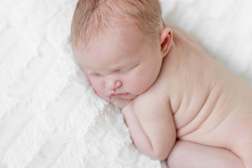 Adorable naked infant sleeping on his belly