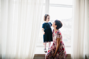 The mother with daughter sitting on the window-sill