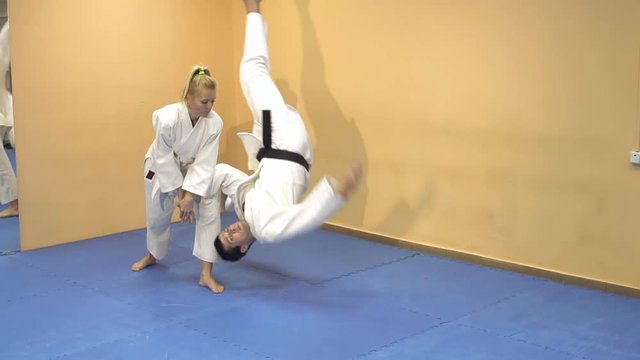 Martial arts master in a white kimono practice Aikido with a woman.