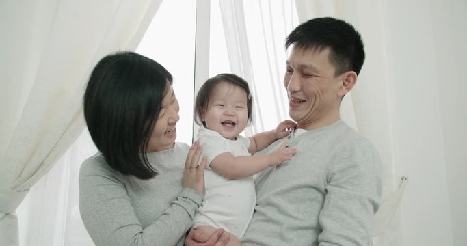 slow motion, young happy Asian couple with a little girl in the bedroom,happy moments in the family