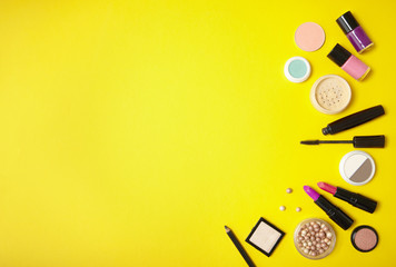 Make up and cosmetic products arranged on a vibrant yellow background, with blank space at side