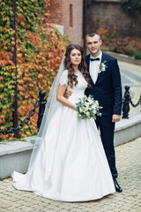 Naklejka premium Portrait of beautiful wedding couple posing before wall with yellow ivy