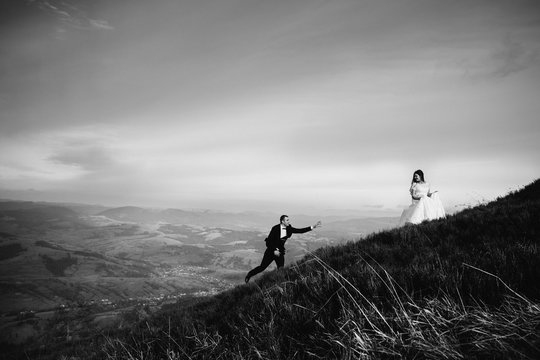 Clouds Spread Over Stunning Wedding Couple Walking Up The Hill