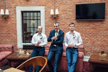 Fototapeta na wymiar Laughing men drink whisky standing before red sofa