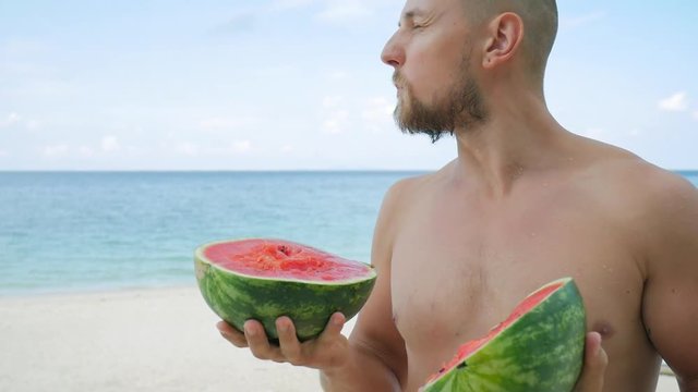Young Handsome Bearded Hipster Eating Tasty Watermelon on the Beach. Phangan, Thailand. HD Slowmotion.