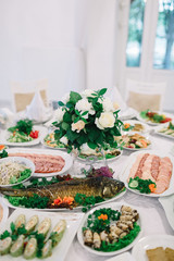 Fish and meat served on white dishes stand on dinner table