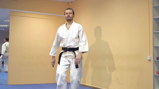 Man in a white kimono demonstrating martial arts techniques, slow motion.