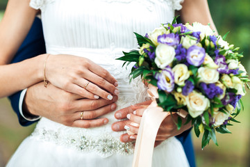 Bride hands with ring and wedding bouquet of flowers