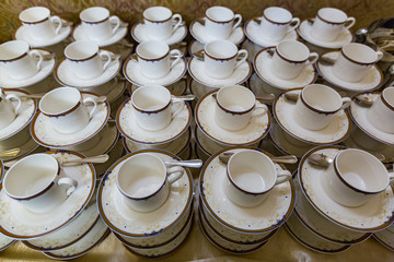 Rows of white porcelain empty cups with saucers for tea and coffee