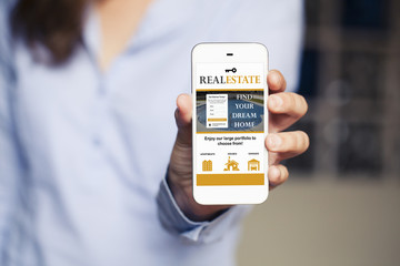 Real estate website in a mobile phone screen. Woman holding phone in the hand.