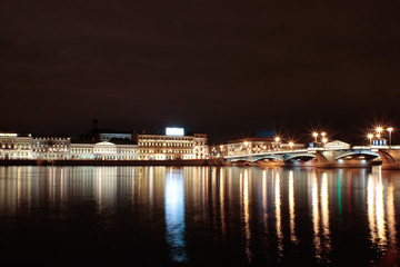 Night long shutter exposure photo of river and relflected lights of buildings and bulbs in Saint Petersburg, Russia