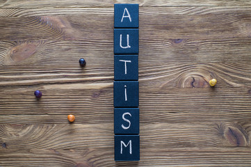 Word Autism built of black wooden blocks on a wooden background with copy space, top view, flat lay. Concept of autism word, flat lay. Autism Spectrum Disorder (ASD).  Autism awareness.