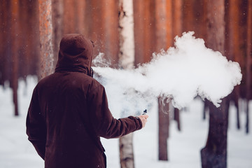 vaping man holding a mod device. cloud of vapor. Vape