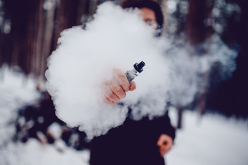 vaping man holding a mod device. cloud of vapor. Vape