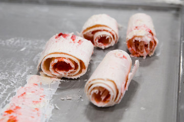 Detail of strawberry rolled ice cream on cold plate.