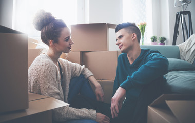 Couple moving in new home and relaxing on floor after unpacking boxes
