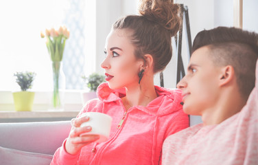 Couple in pink clothes relaxing on sofa at home