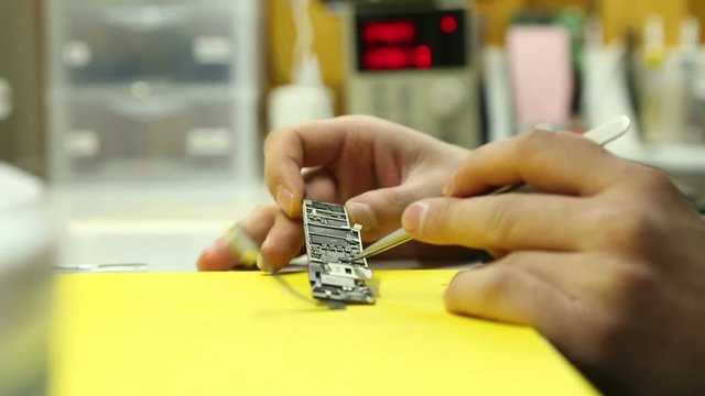 repair shop carries out the repair of smartphones under warranty soldering electronic boards cleaning purging test setup