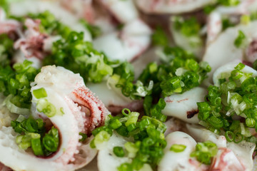 Dish of tentacles octopus sprinkled with green onions closeup