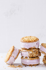 Set of homemade ice cream sandwiches in oat cookies with almond sugar crumbs over gray texture background. Copy space