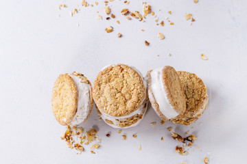Set of homemade ice cream sandwiches in oat cookies with almond sugar crumbs over gray texture...