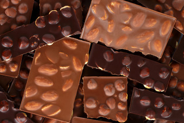 Broken chocolate bars with nuts background