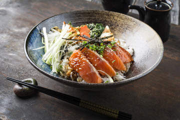 Traditional Japanese Salmon Sashimi with Rice and Vegetable as close-up in a bowl