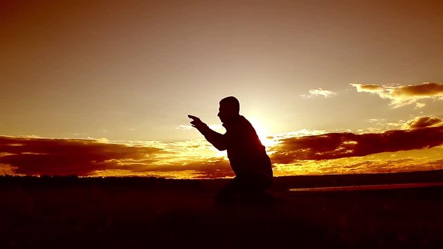Silhouette of a man praying at sunset concept of religion. Image of silhouette man praying with sunset background