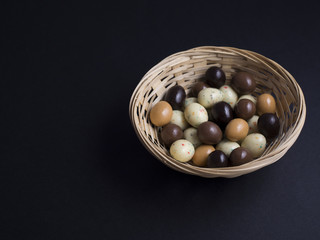Chocolate easter eggs in wooden basket isolated on black background