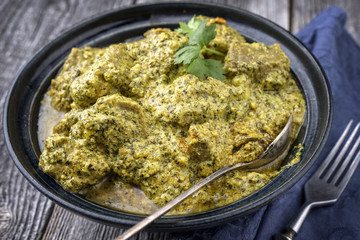 Traditional Indian Lamb Curry with Mint and Coriander as close-up in a Korai