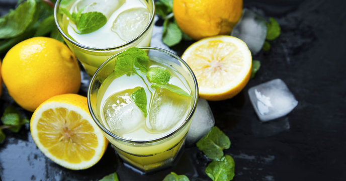 Lemon cocktails with mint and ice cubes on dark background, mojitos ingredients