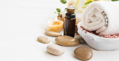 Spa setting with essence bottle, cotton towel,massage stones and candle