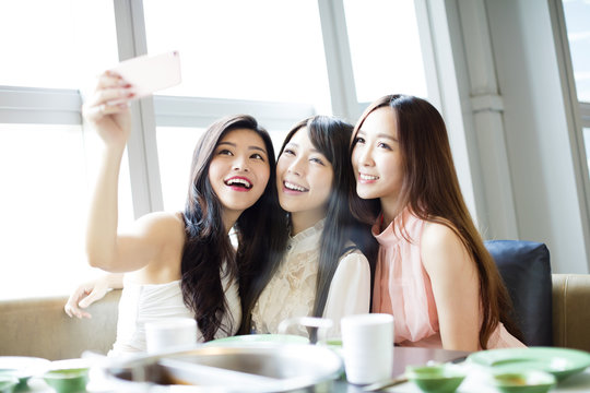  happy young girl friend taking selfie together in restaurant