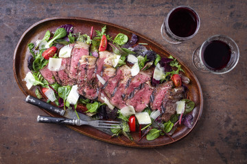 Italienisches Tagliata Steak mit Parmesan und Salat als Draufsicht auf Teller