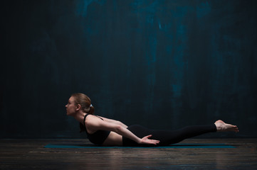 Fototapeta na wymiar Young flexible woman doing yoga on blue mat