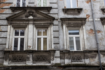 Three Vintage design windows on the facade of the ragged old house