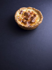 Small quiche lorraine pie isolated on black background