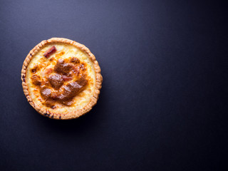 Small quiche lorraine pie isolated on black background