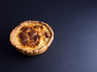 Small quiche lorraine pie isolated on black background