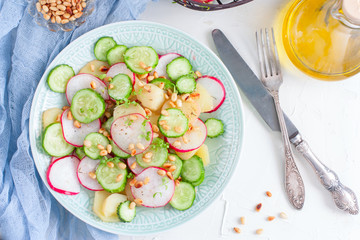 Salad from potatoes, radishes, cucumbers with pine nuts, top view