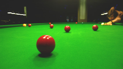 One man plays Billiards. Bright colorful balls to play snooker. Dim lights
