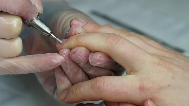 Cleaning of cuticles on female fingers. Woman in a nail salon receiving a manicure