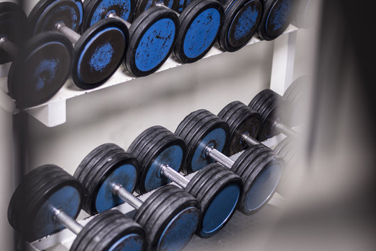 Old school gym interior with equipment, bodybuilding background. Heavy iron dumbbells stacked in rows.