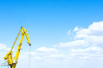 Harbor crane against the blue cloudy sky.