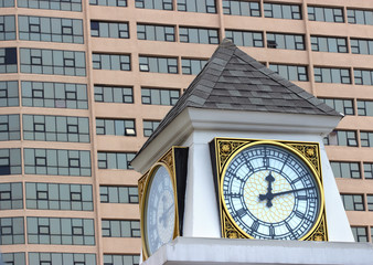 Fototapeta na wymiar Часы на башне на фоне современного здания