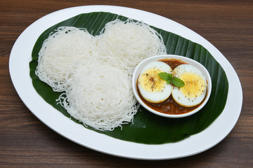 Noolappam/Idiyappam/rice noodles, a popular traditional steam cooked Kerala breakfast dish with hot and spicy egg roast curry on a houseboat, Alleppey, India. South Indian food. noolputtu Sri lankan